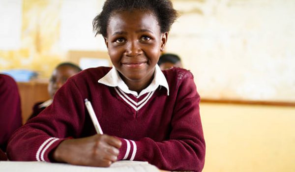 South African girl (from the Xhosa tribe) works on her studies at an old worn desk in a class room in the Transkei region of rural South Africa.